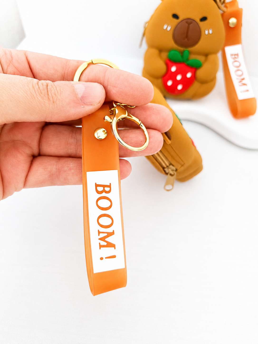 Bracelet porte-clés orange BOOM! avec anneau doré et porte-monnaie Capybara en arrière-plan